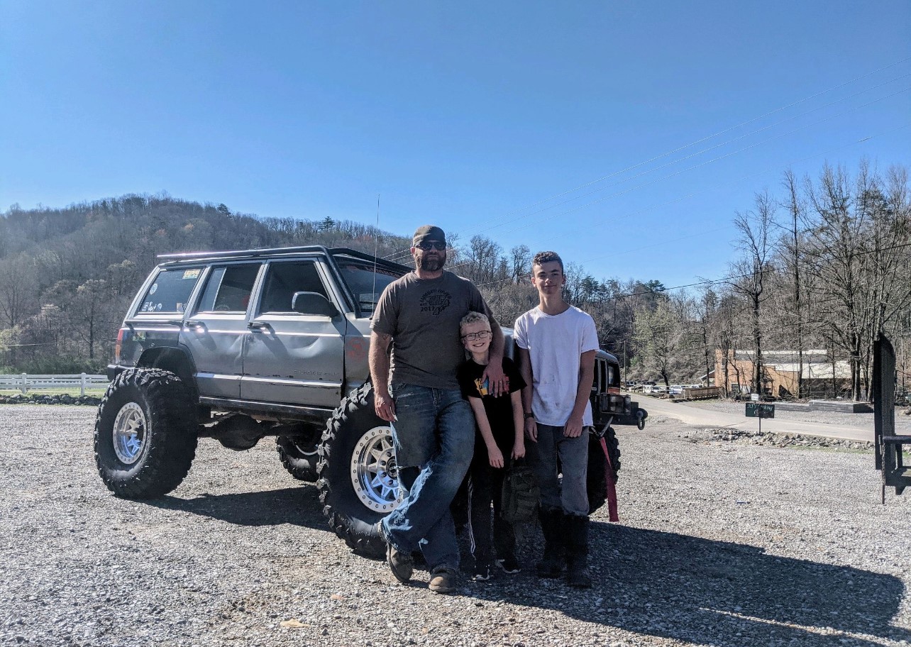 The Watkins family posing with their lifted Jeep Cherokee